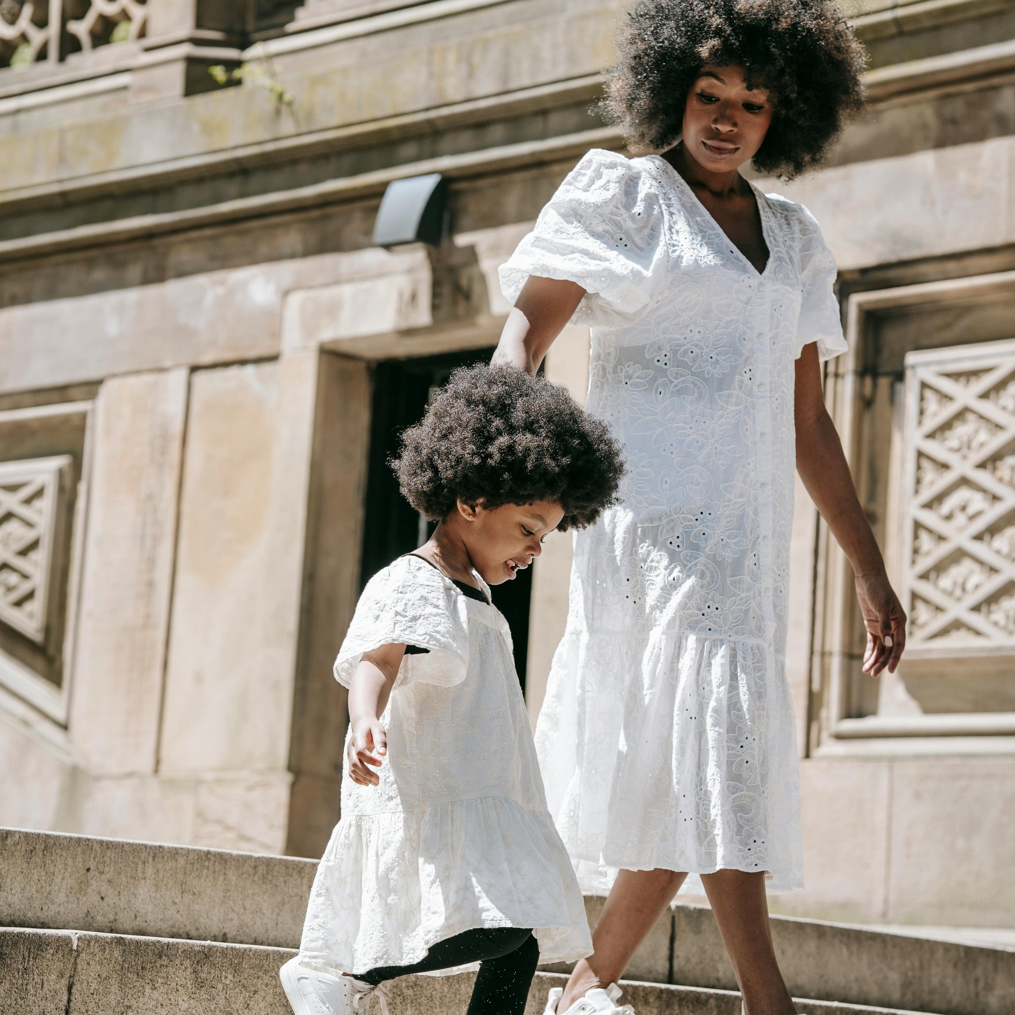 A mother folds gently used baby clothes at a kitchen table with natural light, surrounded by cardboard boxes ready for donation or swap, highlighting sustainable parenting choices.