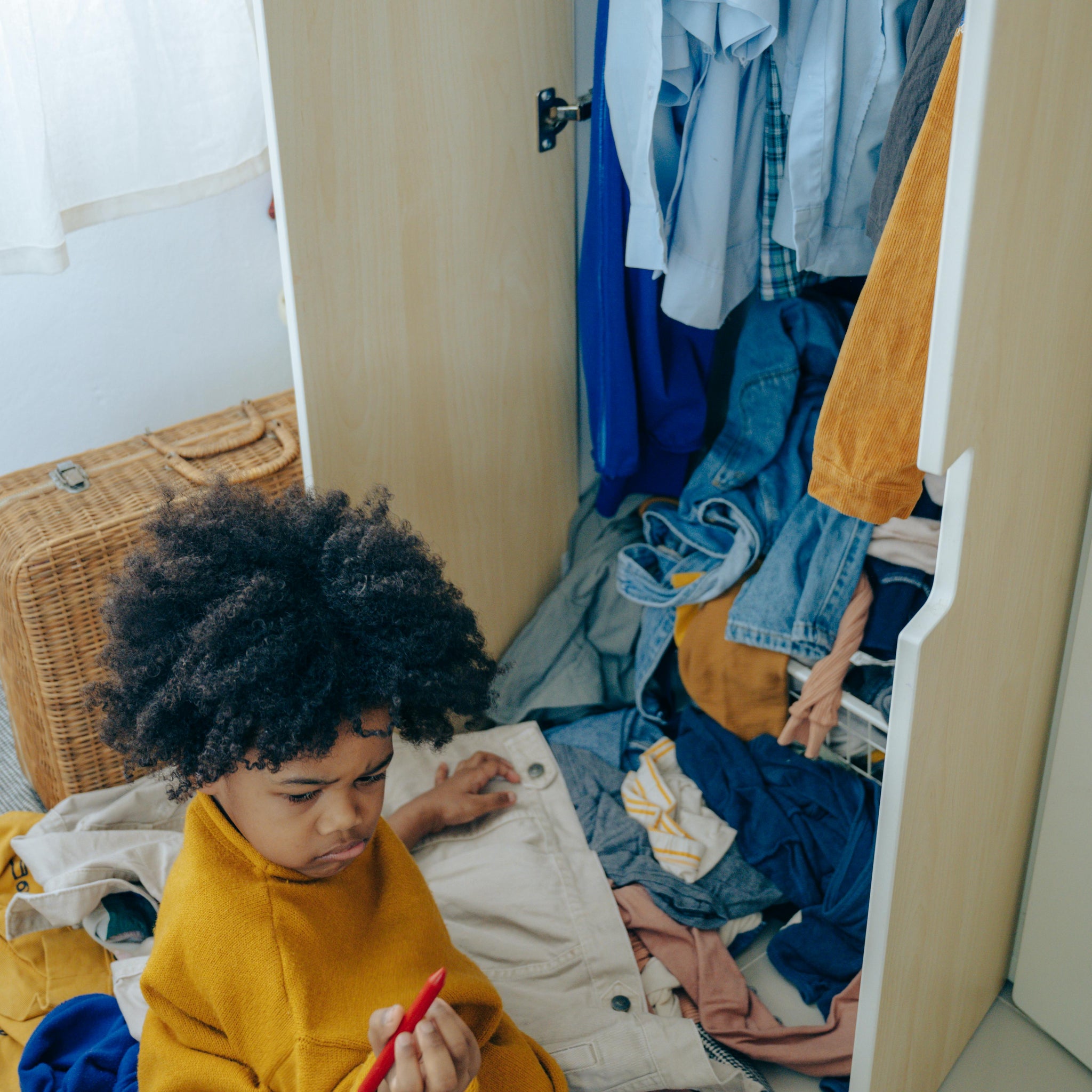A kid sorts through kids clothing to form a toddler capsule wardrobe